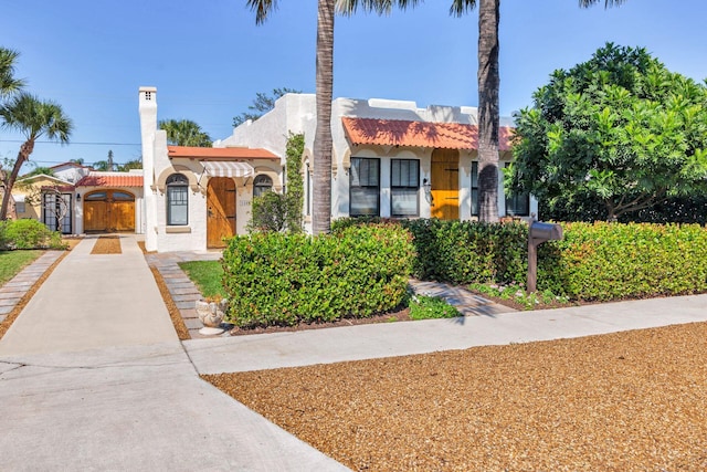 view of front of property featuring a gate, a tile roof, and stucco siding