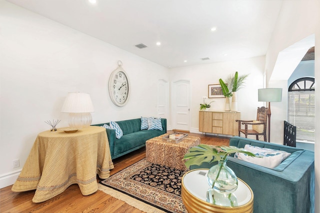 living room with recessed lighting, visible vents, baseboards, and wood finished floors