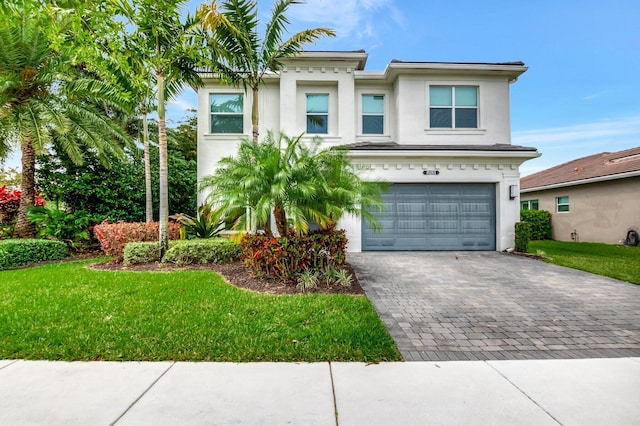 view of front of home with decorative driveway, a garage, a front lawn, and stucco siding