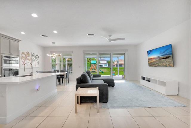 living area featuring ceiling fan with notable chandelier, light tile patterned floors, recessed lighting, and visible vents