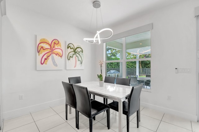 dining space with an inviting chandelier, light tile patterned flooring, and baseboards