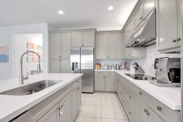 kitchen with tasteful backsplash, stainless steel fridge with ice dispenser, under cabinet range hood, black electric cooktop, and a sink