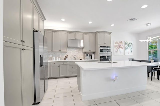 kitchen with under cabinet range hood, gray cabinets, stainless steel appliances, and a sink