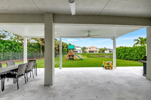 view of patio featuring outdoor dining space, ceiling fan, a playground, and a fenced backyard