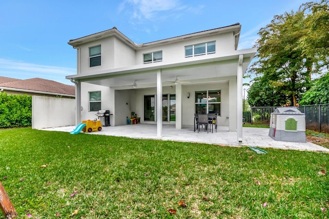 rear view of house with ceiling fan, fence, stucco siding, a yard, and a patio