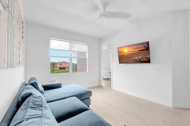 living area featuring ceiling fan, baseboards, and wood finished floors