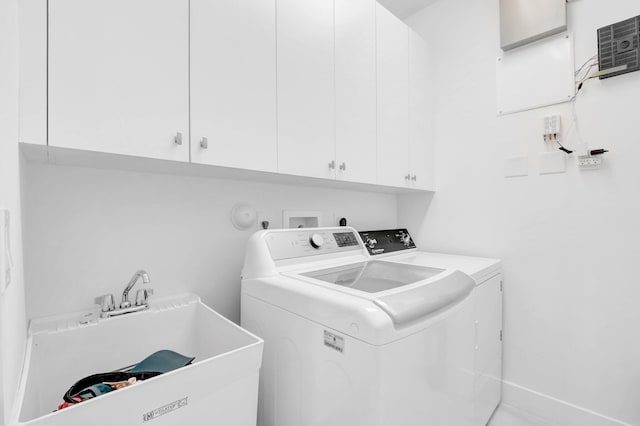 clothes washing area with cabinet space, washing machine and dryer, and a sink