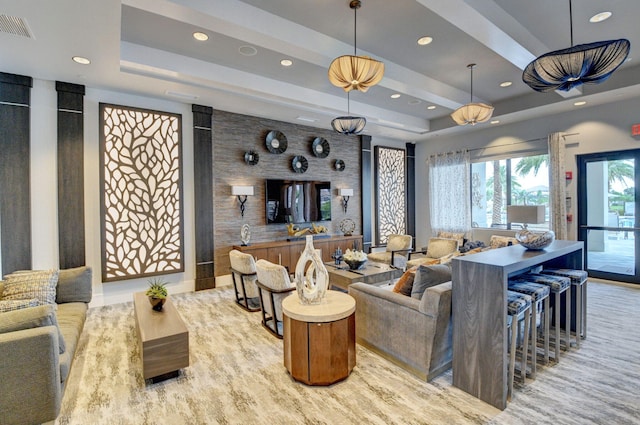 living room with a tray ceiling, recessed lighting, and visible vents