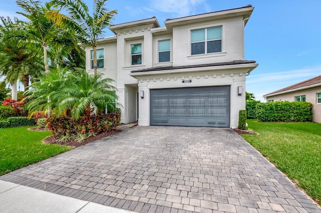 view of front of house with stucco siding, a front yard, decorative driveway, and a garage