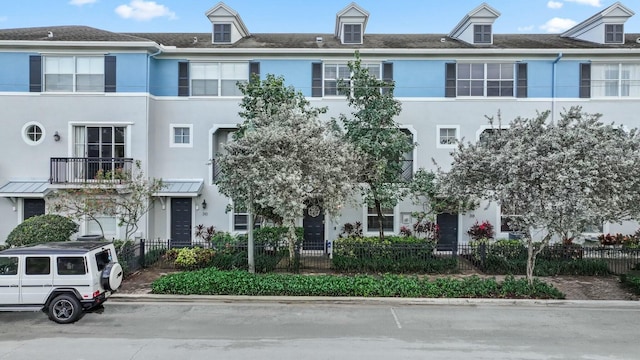 townhome / multi-family property featuring a fenced front yard and stucco siding