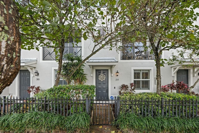 view of front facade featuring a standing seam roof, a fenced front yard, metal roof, and stucco siding