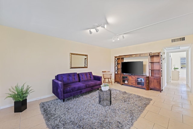 living room with track lighting, visible vents, baseboards, and light tile patterned floors