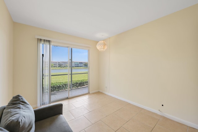 unfurnished living room with a water view, light tile patterned flooring, and baseboards