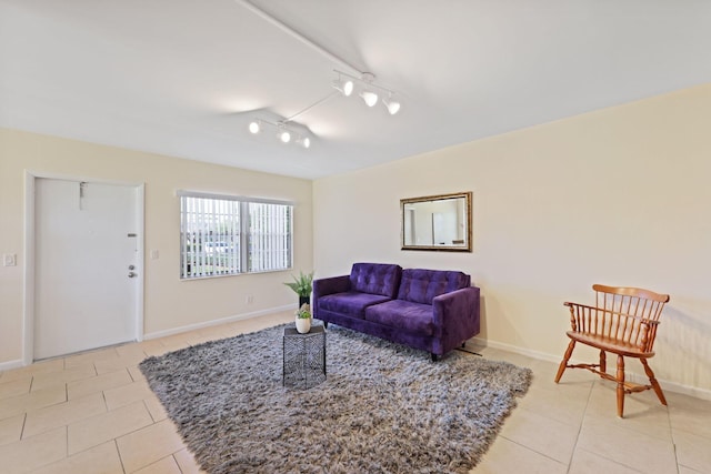 living area featuring track lighting, light tile patterned flooring, and baseboards