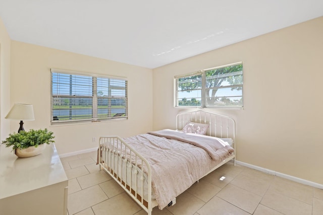 bedroom featuring light tile patterned floors, multiple windows, and baseboards