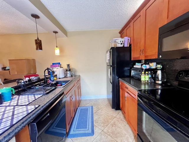 kitchen with brown cabinetry, a textured ceiling, black appliances, a sink, and light tile patterned flooring