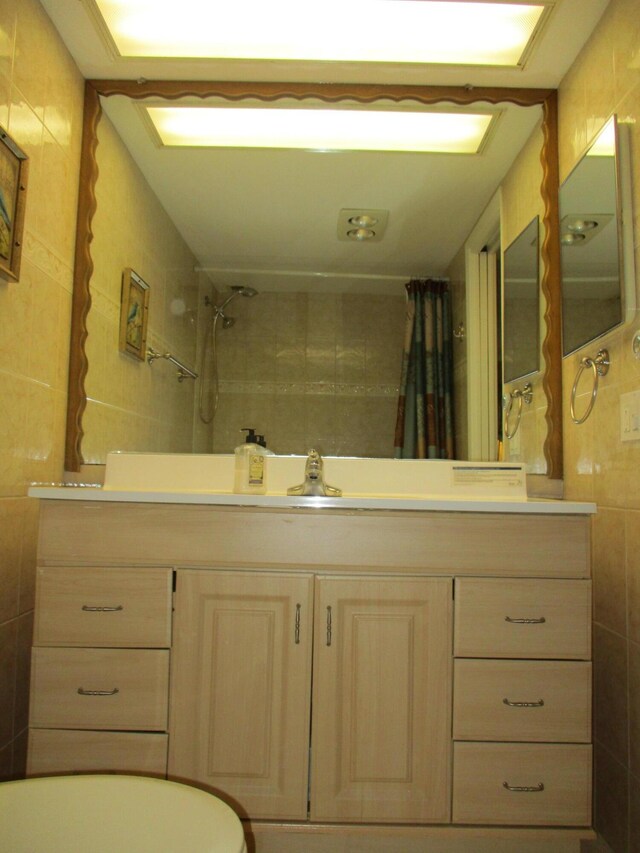 full bath with curtained shower, tile walls, and vanity