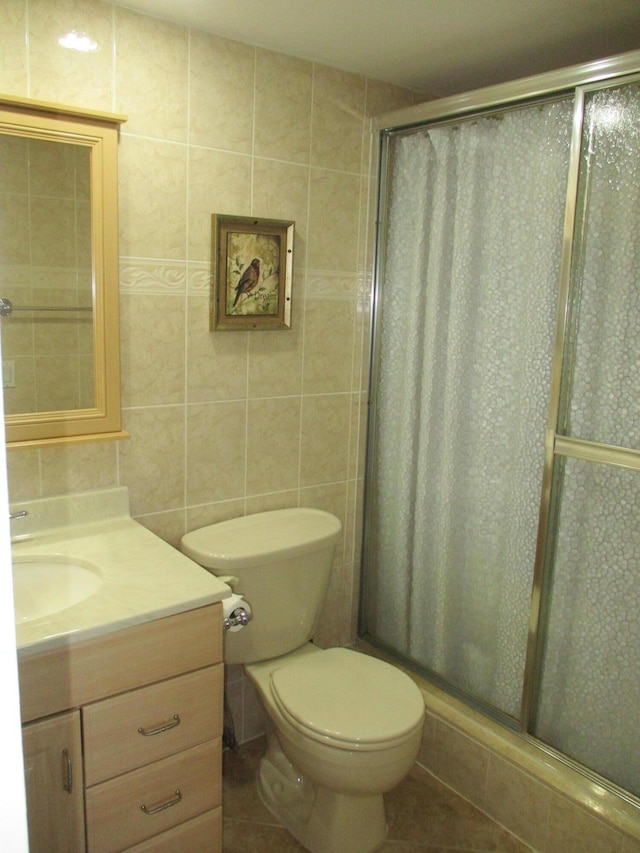 bathroom with tile patterned flooring, a shower stall, tile walls, and vanity