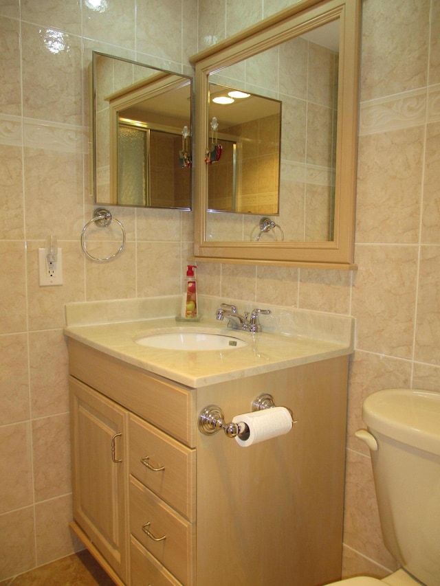 bathroom featuring tasteful backsplash, toilet, tile walls, and vanity