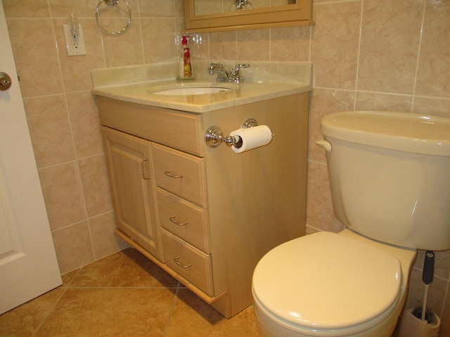 half bathroom featuring toilet, vanity, tile walls, and tile patterned floors