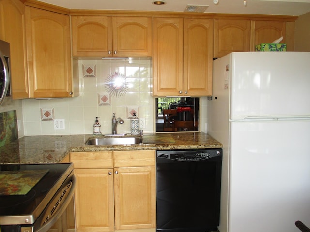 kitchen with a sink, black dishwasher, freestanding refrigerator, decorative backsplash, and dark stone countertops