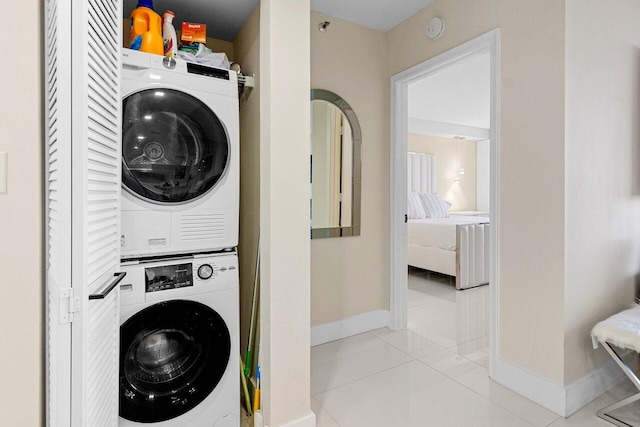 laundry area featuring baseboards, stacked washer and dryer, laundry area, and tile patterned floors