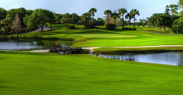 view of property's community with view of golf course, a yard, and a water view