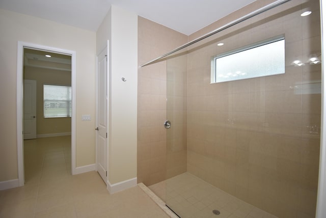 bathroom featuring tile patterned flooring, baseboards, and tiled shower