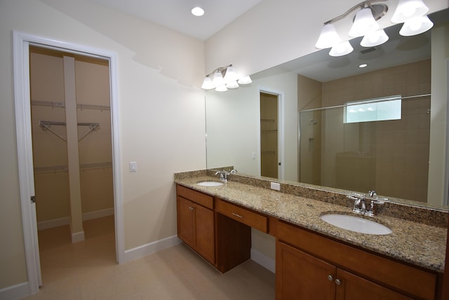 full bathroom featuring baseboards, double vanity, a sink, and a shower stall