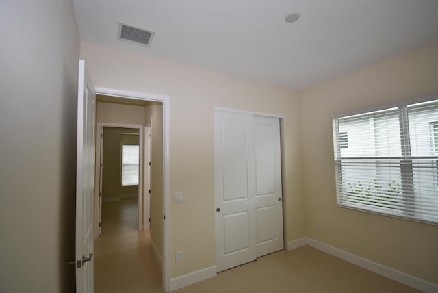 unfurnished bedroom with baseboards, visible vents, and a closet