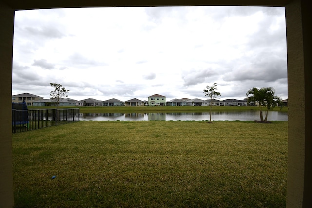 view of yard featuring a water view, fence, and a residential view