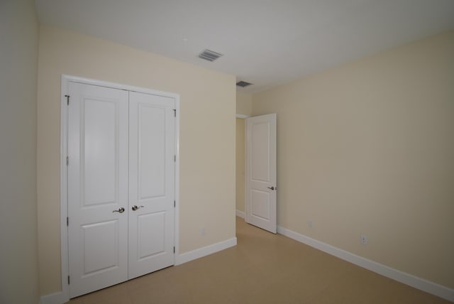 unfurnished bedroom with a closet, visible vents, and baseboards