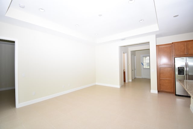 empty room featuring recessed lighting, a raised ceiling, and baseboards