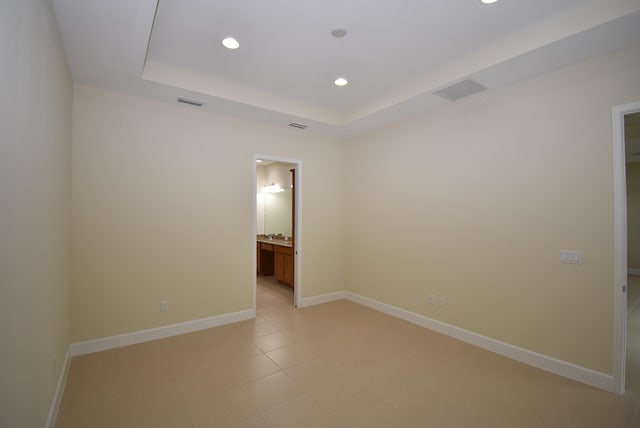 spare room featuring a tray ceiling, visible vents, baseboards, and recessed lighting