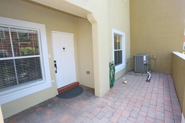 entrance to property featuring cooling unit and stucco siding