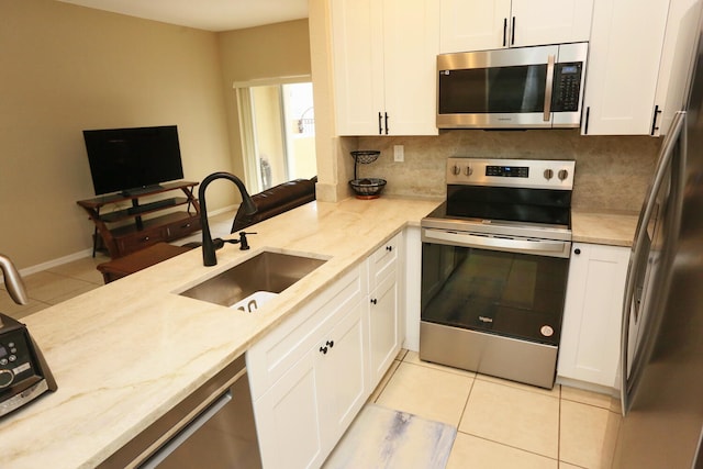 kitchen with stainless steel appliances, backsplash, a sink, and white cabinetry