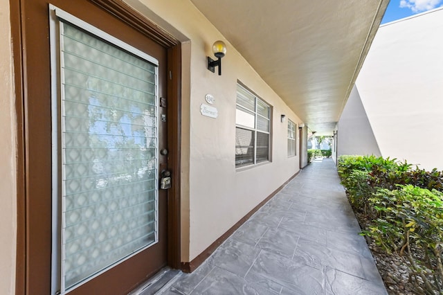 view of exterior entry featuring covered porch and stucco siding