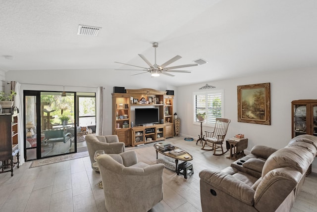 living area with visible vents, ceiling fan, vaulted ceiling, a textured ceiling, and light wood-type flooring