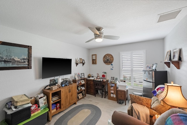 living room featuring light carpet, ceiling fan, a textured ceiling, and visible vents