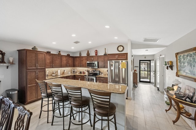 kitchen with tasteful backsplash, visible vents, lofted ceiling, a center island, and stainless steel appliances