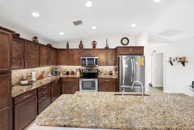 kitchen featuring visible vents, backsplash, appliances with stainless steel finishes, vaulted ceiling, and light stone countertops