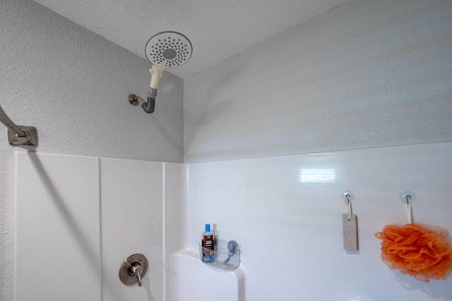 details featuring a textured wall, a shower, and a textured ceiling