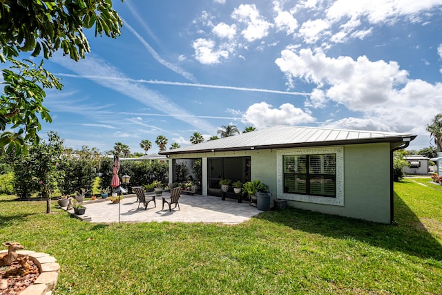 rear view of property with metal roof, a patio, a yard, and stucco siding