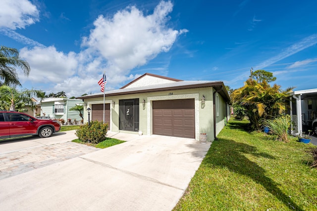 single story home with a garage, concrete driveway, a front yard, and stucco siding