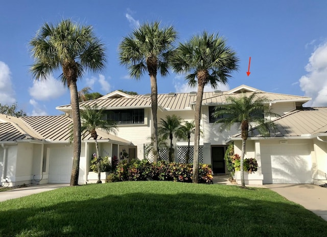 view of front of house with metal roof, a front yard, driveway, and a standing seam roof