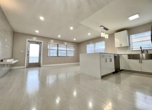 kitchen with baseboards, a peninsula, light wood-type flooring, white cabinetry, and a sink