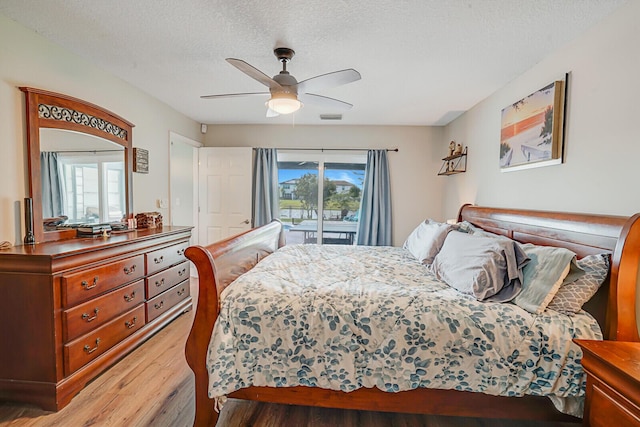 bedroom with visible vents, light wood-style flooring, access to outside, a textured ceiling, and ceiling fan