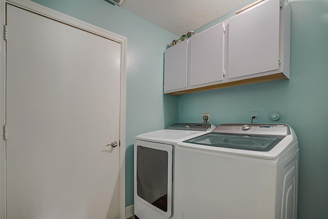 washroom with washer and clothes dryer, cabinet space, and a textured ceiling