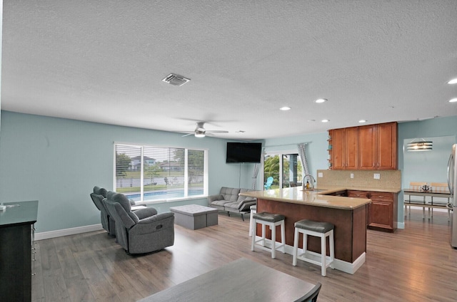 living area with a ceiling fan, visible vents, and light wood finished floors