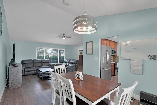 dining space with visible vents, ceiling fan with notable chandelier, lofted ceiling, and wood finished floors